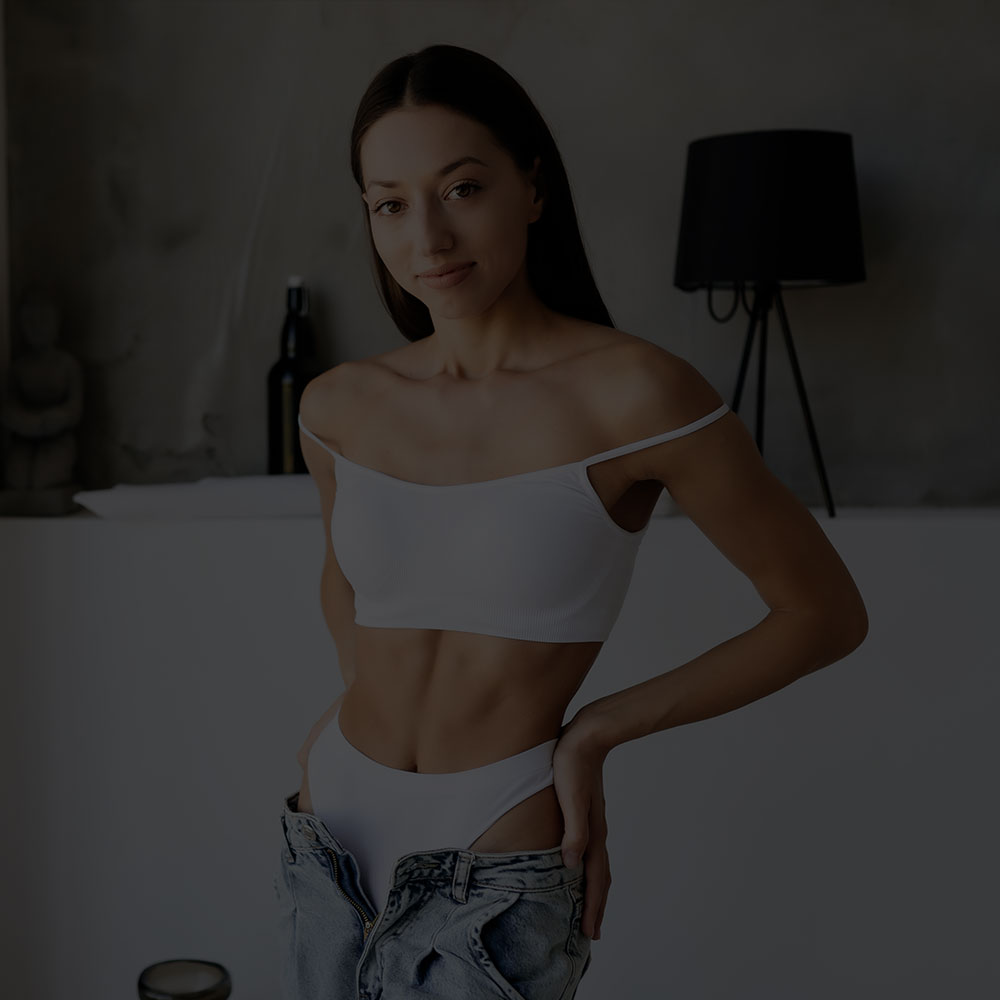 Happy thin woman walking on the beach in jean shorts and a bikini top after gastric bypass